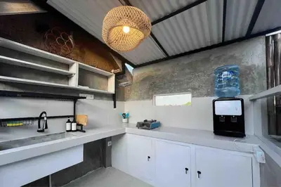 a kitchen with white cabinets and a sink and a television at Little Farm House Kerobokan near Seminyak in Kerobokan