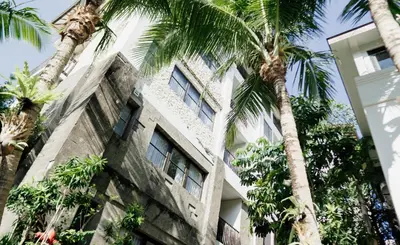 an old building with palm trees in front of it at Esco Luxe Jimbaran in Jimbaran