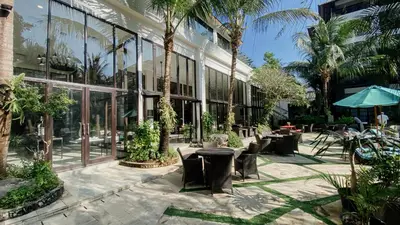 a courtyard with tables and chairs and palm trees at Esco Luxe Jimbaran in Jimbaran