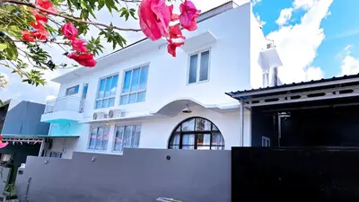 a white house with pink flowers in front of it at MauLagi Bali Getaway in Jimbaran