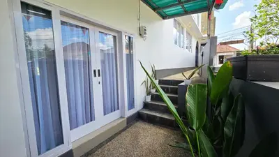 a balcony of a house with stairs and a plant at MauLagi Bali Getaway in Jimbaran