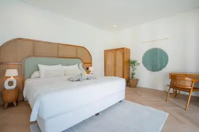 a bedroom with a large white bed and a desk at Villa Palma Blanca Canggu by Nagisa Bali in Canggu