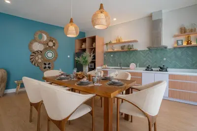 a dining room with a wooden table and white chairs at Villa Palma Blanca Canggu by Nagisa Bali in Canggu