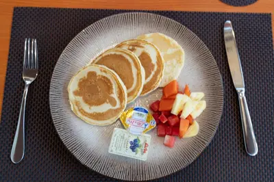 a plate with pancakes and fruit on a table at Villa Palma Blanca Canggu by Nagisa Bali in Canggu
