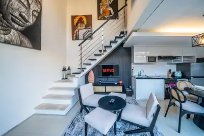 a staircase in a living room with chairs and a table at Villa Lotus by Unicorn Villas Bali in Kerobokan
