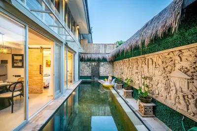 a house with a swimming pool next to a wall at Villa Lotus by Unicorn Villas Bali in Kerobokan