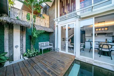 a house with a wooden deck with a dining area at Villa Lotus by Unicorn Villas Bali in Kerobokan