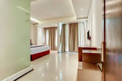 a hotel room with a bed and a desk at Dancenter Premium Legian Hotel in Balian
