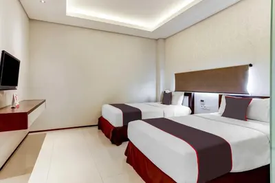 a hotel room with two beds and a tv at Dancenter Premium Legian Hotel in Balian