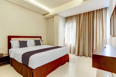 a hotel room with a large bed and a window at Dancenter Premium Legian Hotel in Balian