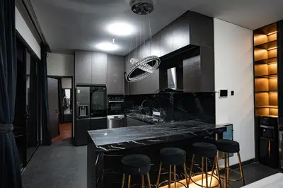 a kitchen with a black counter and bar stools at Villa Maya in Kerobokan