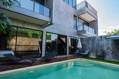 a house with a swimming pool next to a building at Villa Maya in Kerobokan