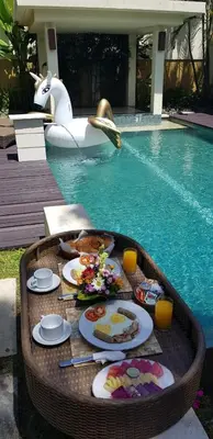 a table with plates of food in a swimming pool at Privat Pool Villa with Kitchen at seminyak in Seminyak