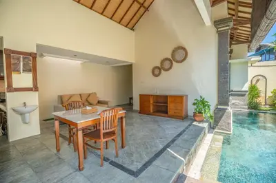 a living room with a table and a swimming pool at Classic Pool villa with kitchen in Seminyak