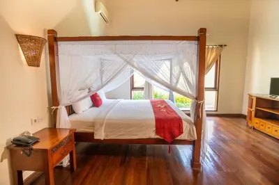 a bedroom with a canopy bed and a wooden table at Classic Pool villa with kitchen in Seminyak