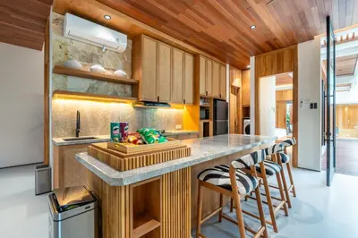 a kitchen with wooden cabinets and a counter with bar stools at Gelareh Villa Berawa in Canggu