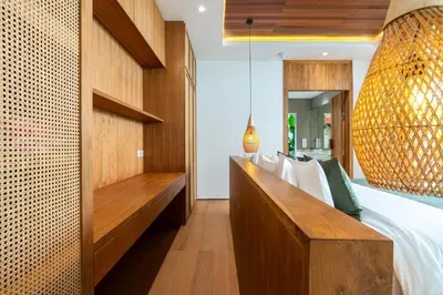 a bedroom with a bed with a wooden bench at Gelareh Villa Berawa in Canggu