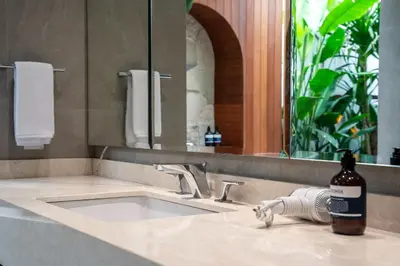 a bathroom sink with a bottle of alcohol on it at Gelareh Villa Berawa in Canggu