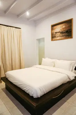 a bedroom with a large bed with white sheets at Villa Frankie in Central Legian in Legian