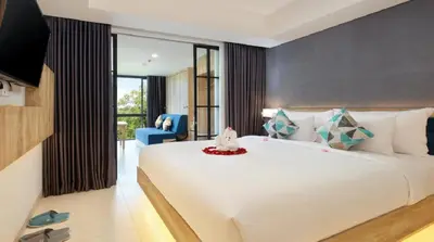 a bedroom with a large white bed and a blue chair at Esco Luxe Benoa in Nusa Dua