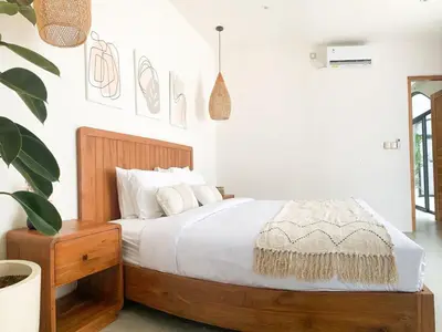 a bedroom with a wooden bed with white sheets at Cozy and Chic Villa with Private Pool at Balangan in Jimbaran