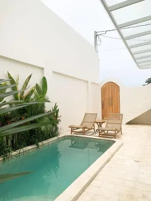 a swimming pool in a house with two chairs at Cozy and Chic Villa with Private Pool at Balangan in Jimbaran