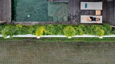 an overhead view of a woman laying on a bench next to a pool at Villa Rice - Amazing Rice-Field VIEW 3BR Villa 9px Next To Canggu in Kerobokan