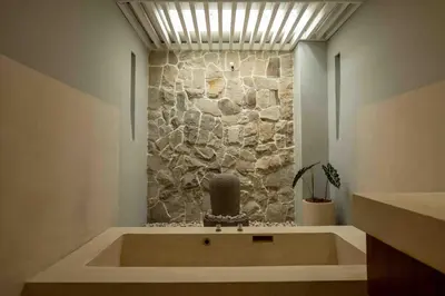 a bath tub in a room with a stone wall at Tuluscolivingseminyakvilla1 in Seminyak