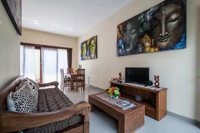 a living room with a couch and a tv at The Lavana Villa De Kerobokan in Seminyak