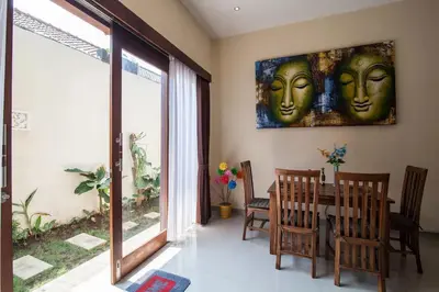 a dining room with a painting of two faces on the wall at The Lavana Villa De Kerobokan in Seminyak