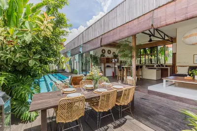 a wooden table and chairs on a patio with a kitchen at Villa Ubuntu 3BR Pool Ricefield Family&Friends group near Canggu in Kerobokan