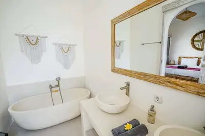 a white bathroom with a tub and a mirror at Villa Vaimala 4BR Pool Tropical Home Seminyak in Seminyak