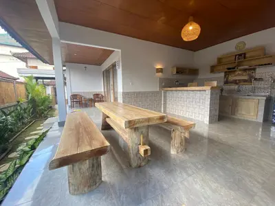 a patio with two wooden benches and a kitchen at Kubu Betel Home Stay in Canggu