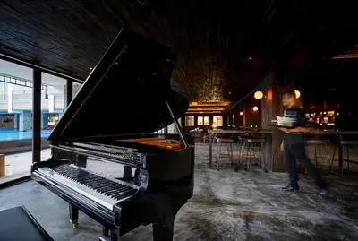 a man standing next to a piano in a bar at The Sintesa Jimbaran Bali in Jimbaran