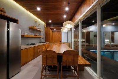 a kitchen with a wooden table and a pool at Anama Villa Kerobokan in Seminyak