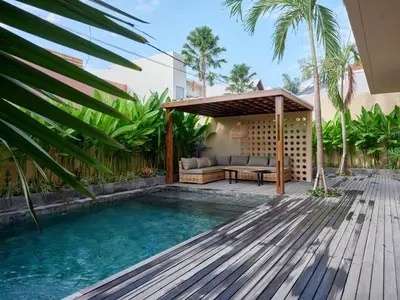 a backyard with a pool and a wooden deck at Villa Papaya Luxurious4bd Umalas in Canggu
