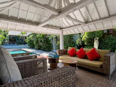 a patio with a couch under an umbrella at Luxurious 5Br Retreat in Umalas in Canggu