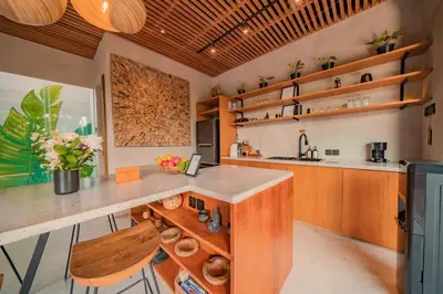 a kitchen with a counter and wooden cabinets and shelves at Villa Cek Ombak 2 Canggu in Canggu