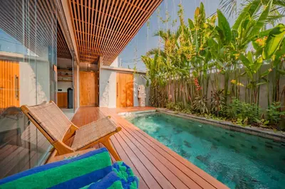 a deck with a chair and a swimming pool at Villa Cek Ombak 2 Canggu in Canggu