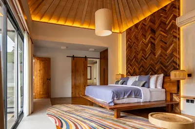 a bedroom with a bed and a wooden wall at tuluscolivingseminyakvilla3 in Seminyak