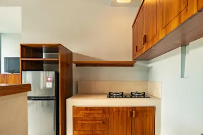 a kitchen with wooden cabinets and a refrigerator at tuluscolivingseminyakvilla3 in Seminyak
