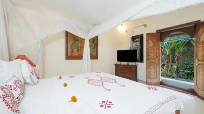 a bedroom with a white bed and a television at Gembira Villa Seminyak in Canggu