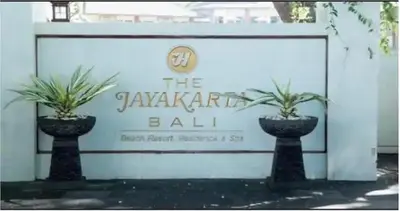 two potted plants sitting in front of a sign at The Palmana Courtyard Jayakarta Residence 4 in Seminyak