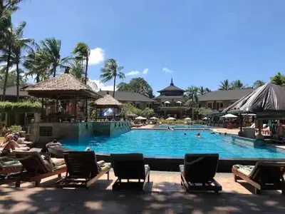 a large swimming pool with chairs and people in it at The Palmana Courtyard Jayakarta Residence 4 in Seminyak