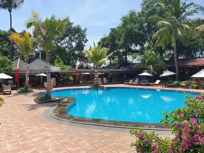a large blue swimming pool with palm trees and umbrellas at The Palmana Courtyard Jayakarta Residence 6 in Seminyak