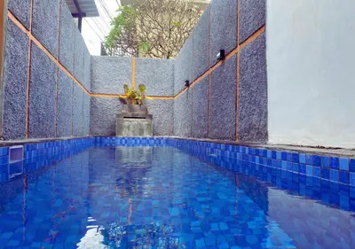 a swimming pool with blue tiled floors and a blue tile wall at Villa Casanomi By Pandara in Kerobokan