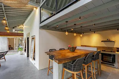 an open kitchen and dining room with a wooden table and chairs at Villa Surga Kecil Seminyak in Seminyak