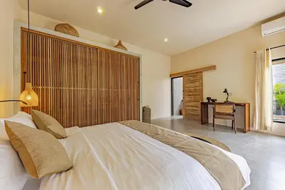 a bedroom with a large white bed and a desk at Villa Surga Kecil Seminyak in Seminyak
