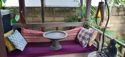 a bench with pillows and a bowl on a porch at Desa Biasa in Kerobokan