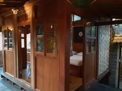 a wooden room with glass doors and a bed at Desa Biasa in Kerobokan